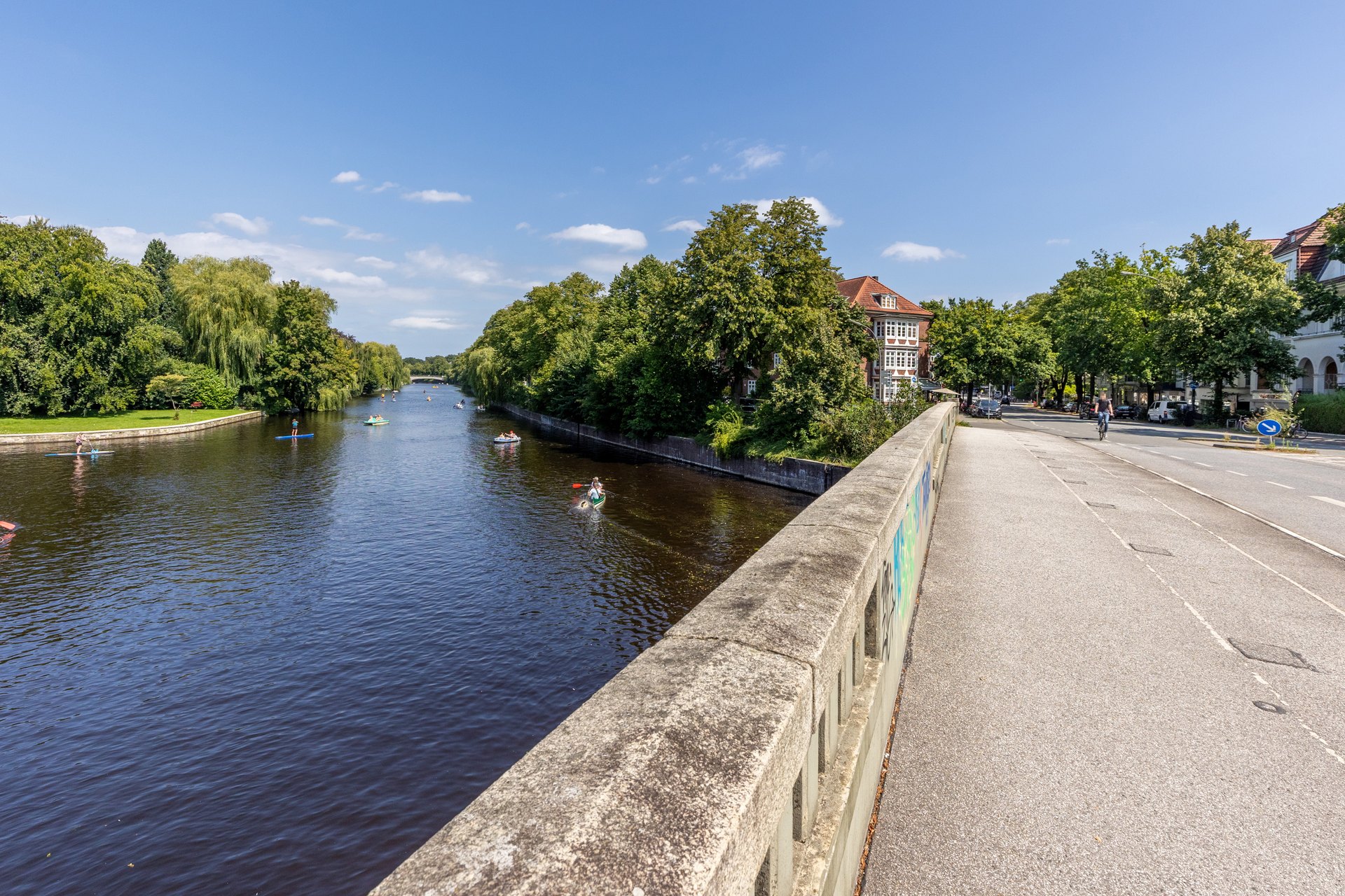 Blick von der Brücke auf die Alster und die grünen Ufer von Winterhude